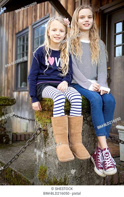 Sisters sitting on mossy pedestal