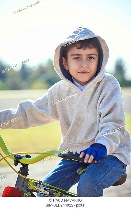 Hispanic boy posing on bicycle