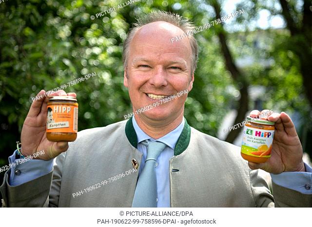 04 June 2019, Bavaria, Pfaffenhofen: Stefan Hipp, Managing Director of Hipp Holding, holds the first glass of baby food from 1960 and the latest Hipp glass in...