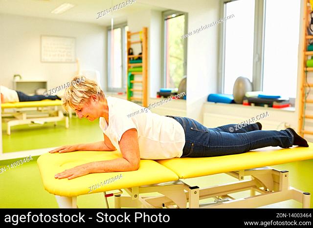 Senior Frau als Patientin mit Rückenschmerzen auf der Massagebank in Physiotherapie Praxis