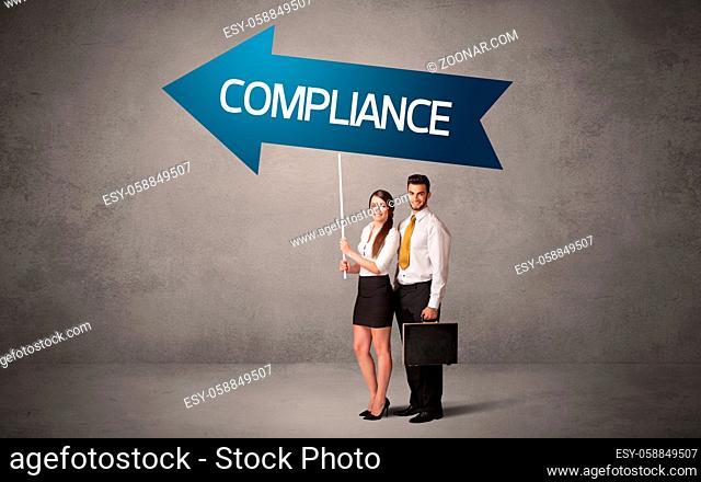 Young business person in casual holding road sign with COMPLIANCE inscription, business direction concept