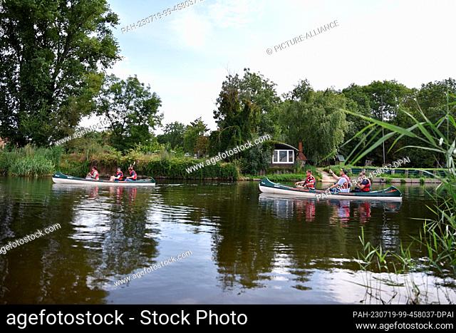 19 July 2023, Saxony-Anhalt, Nienburg: Water sports enthusiasts sit in two canoes and travel across the Bode River near Nienburg (Saale)