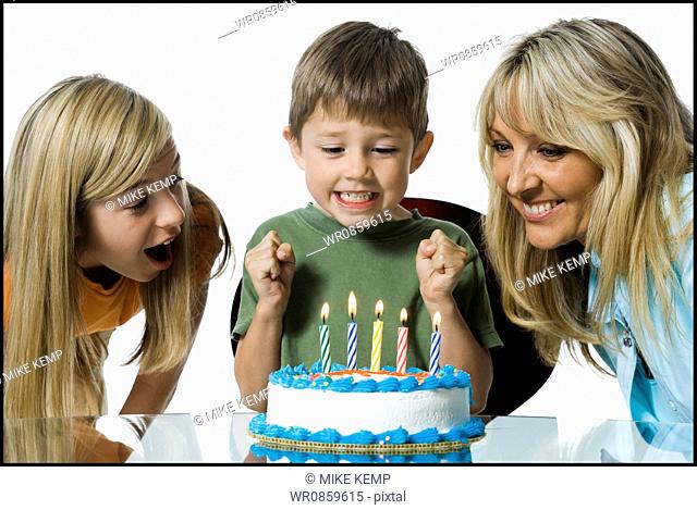 Close-up of a mother and her two children in front of a birthday cake
