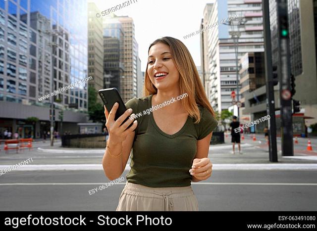 Young female entrepreneur watching her phone on Paulista Avenue in Sao Paulo finance district, Brazil