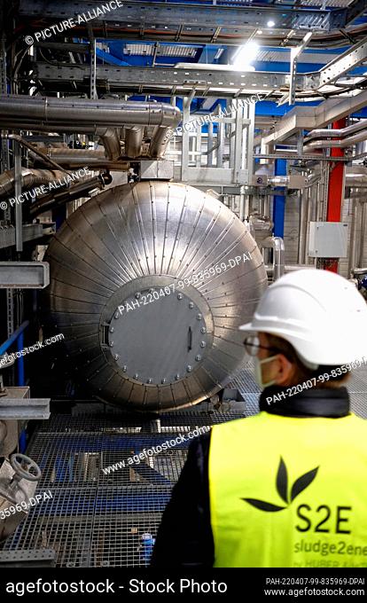 07 April 2022, Hall, Sachsen-Anhalt: An employee of a sewage sludge incineration plant in front of the boiler of a steam turbine
