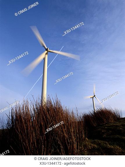 An airliner flies over two wind turbines at the Gilfach Goch Wind Farm near Bridgend and Pontypridd, Mid Glamorgan, Wales, United Kingdom