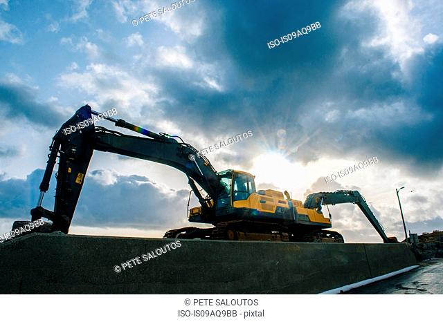Low angle silhouetted view of two excavators parked back to back