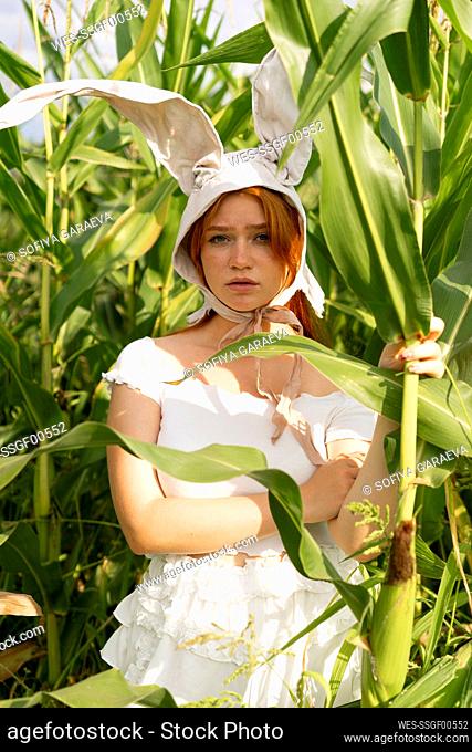 Young woman wearing rabbit costume ears standing in corn farm
