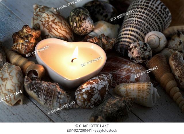 Peaceful heart shaped candle surrounded by sea shells