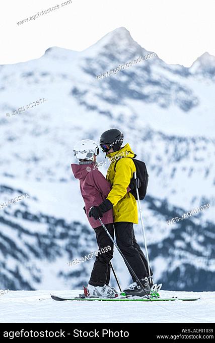 Romantic couple in ski wear embracing at Baqueira Beret resort, Pyrenees, Spain