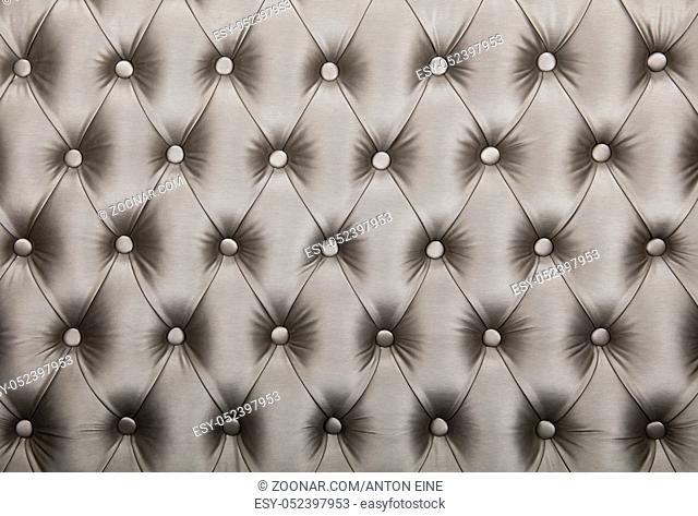 Silver grey capitone textile background, retro Chesterfield style checkered soft tufted fabric furniture diamond pattern decoration with buttons, close up