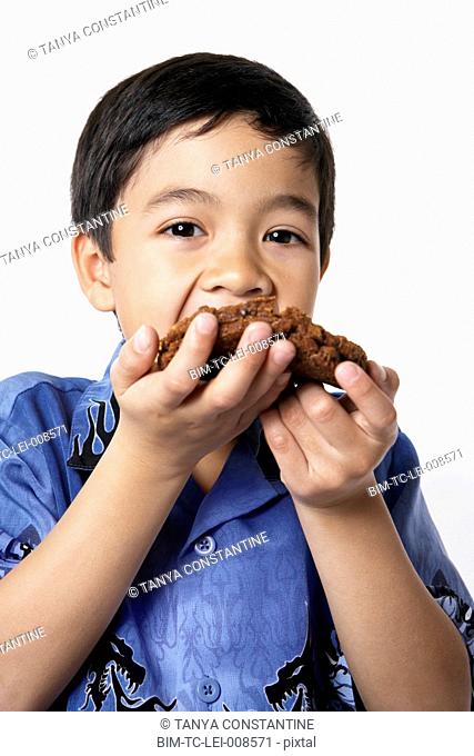 Studio shot of young boy eating cookie