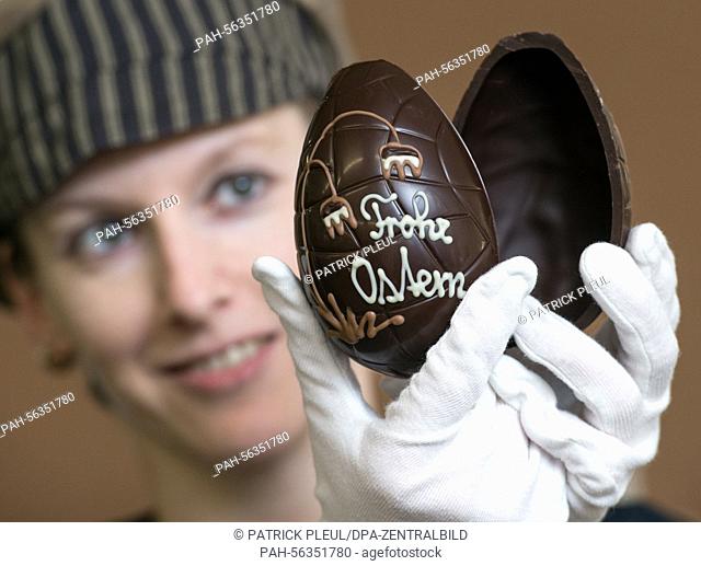 Employee Anke Lubig of the Confiserie Felicitas holds up an Easter egg for the upcoming Easter holiday in Hornow, Germany, 02 March 2015