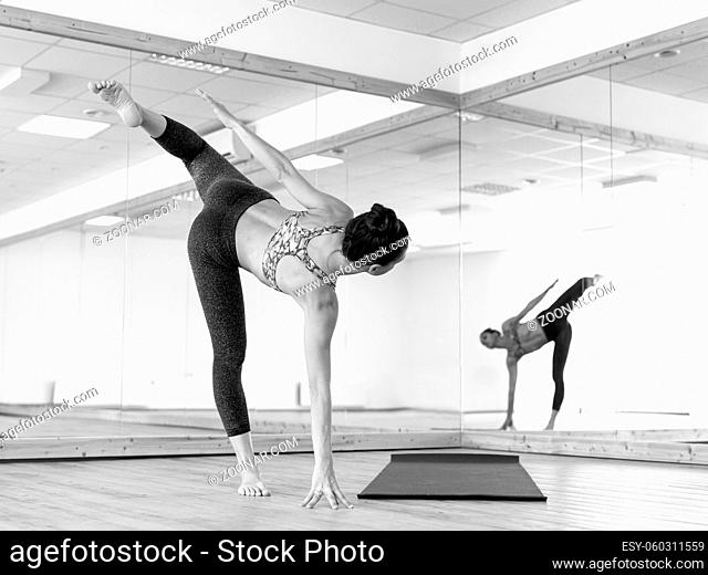 Fit sporty active girl in fashion sportswear doing yoga fitness exercise in in yoga studio. Active urban lifestyle. Black and white photo