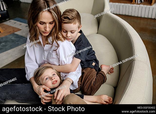 Blond woman sitting with sons on sofa in living room at home
