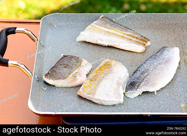 Pictured three fillets of sea bream and codfish cooked on the grill outdoor