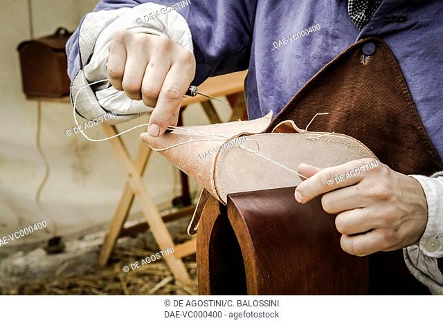 Shoemaker sewing the sole of a pair of shoes, end of the 18th century. Historical reenactment