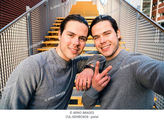 Young adult male twins training together, stairway self portrait