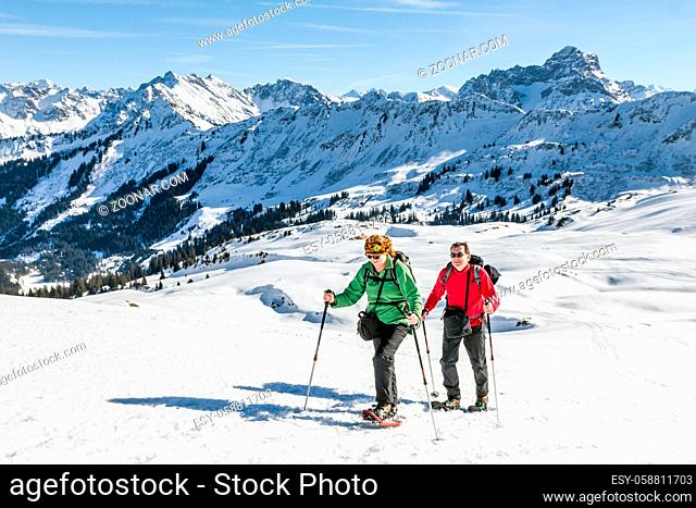 Mature couple hiking with snowshoes in winter mountain landscape. Alps, Germany, Bavaria, Allgau