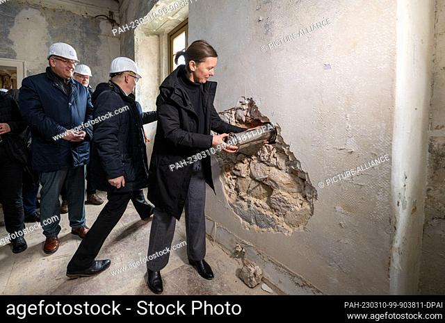 10 March 2023, Saxony-Anhalt, Naumburg: Regine Hartkopf, cathedral architect, slides a time capsule containing objects and writings into the wall of the former...