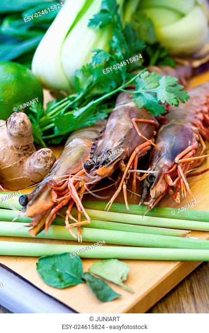 Ingredients for Thai tom yam soup laid out on a kitchen counter with tiger prawns, mushrooms, ginger, lemongrass, limes, celery, parsley and spices