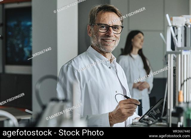 Scientist inventing machinery with female colleague in background at laboratory