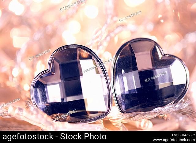 Two jewel hearts on golden shiny light garland background