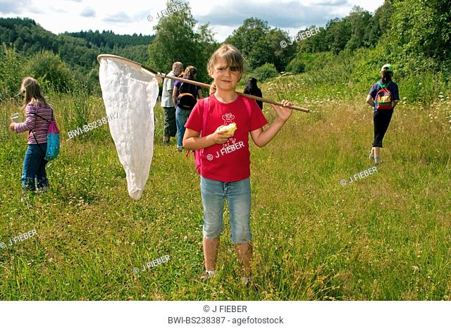 emperor moth Saturnia pavonia, Eudia pavonia, children with leader at a butterfly excursion in a meadow, girl in the foreground with butterfly net over her...