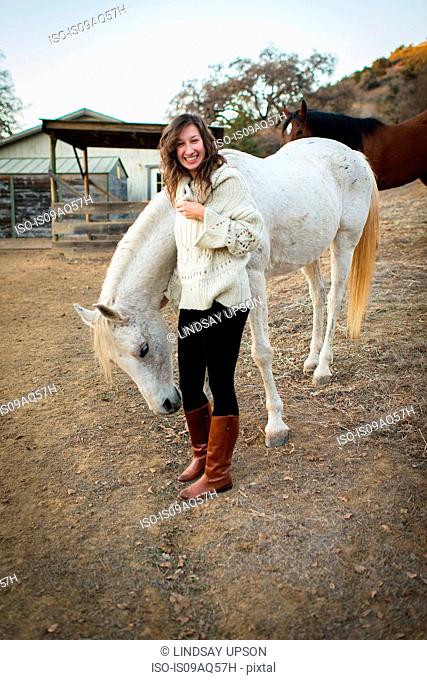 Portrait of young woman petting white horse