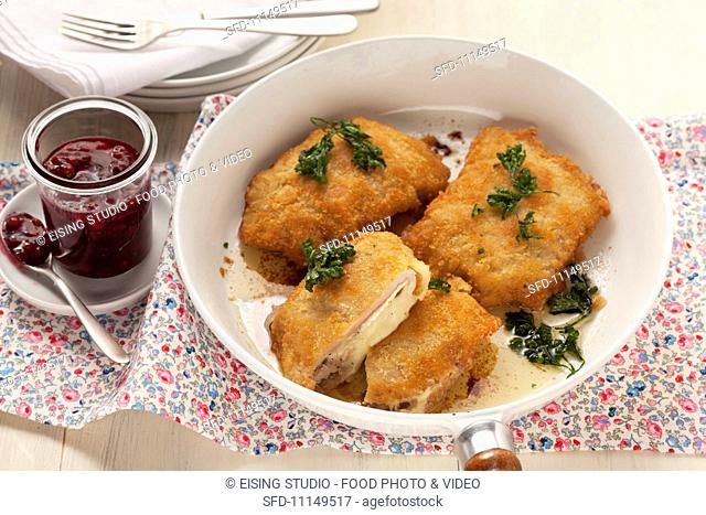 Chicken Cordon Bleu in a frying pan, with cranberry jelly as a condiment