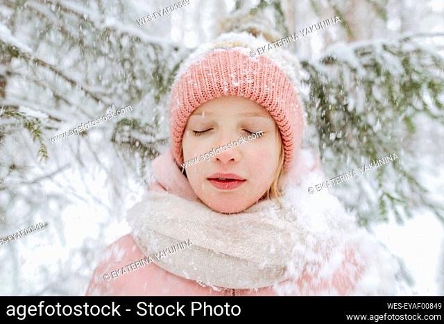 Portrait of girl with eyes closed in winter forest