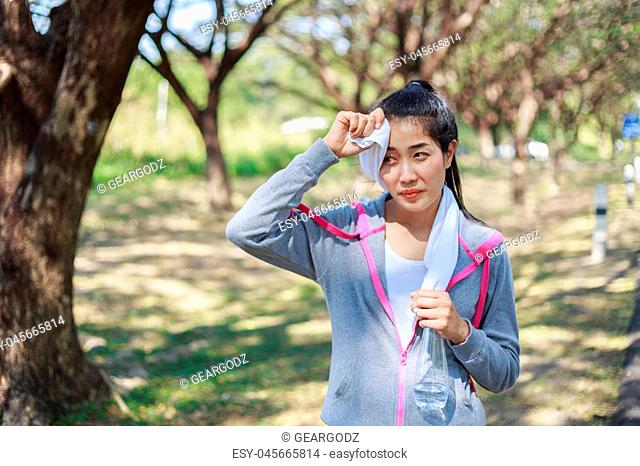 young sporty woman resting and wiping her sweat with a towel after workout sport exercises outdoors at the park