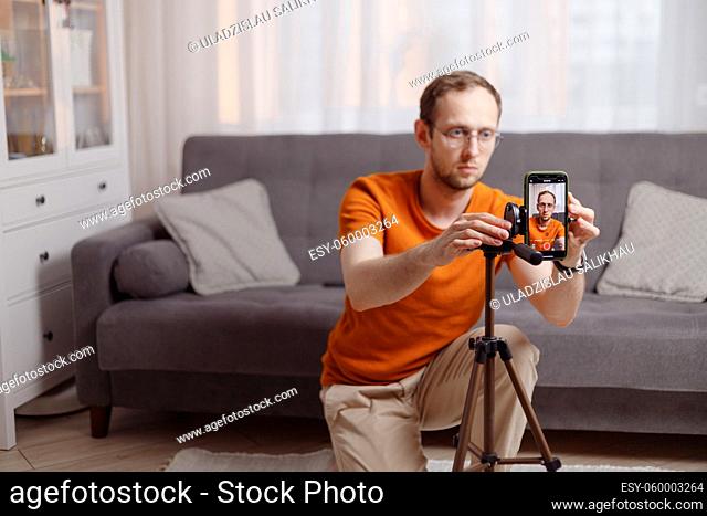 Being blogger. Caucasian smart young man starting video conference at home with smartphone