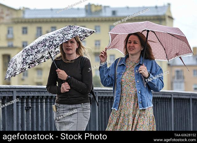 RUSSIA, MOSCOW - JULY 23, 2023: Two women walk under an umbrella along the Krymsky Bridge. Sofya Sandurskaya/TASS