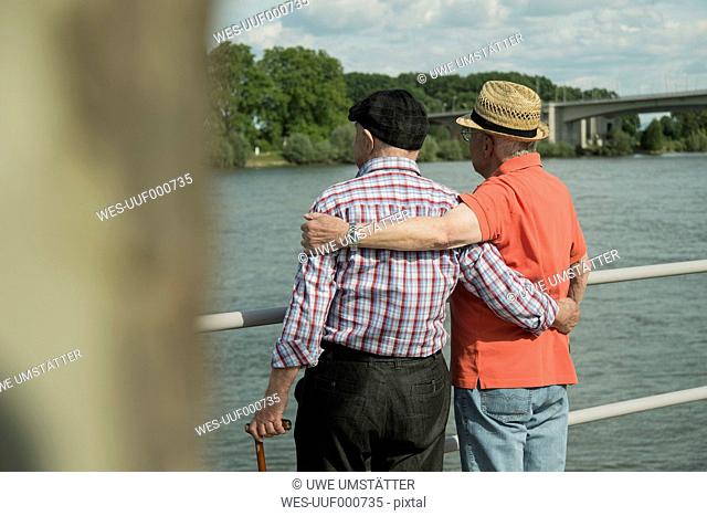 Germany, Rhineland-Palatinate, Worms, two old men standing arm in arm looking at Rhine River, back view