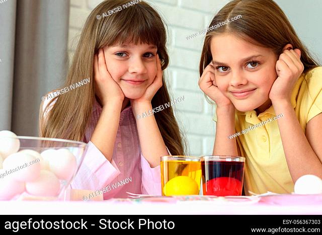 Two girls are waiting for the eggs to be painted in different colors for the Easter holiday