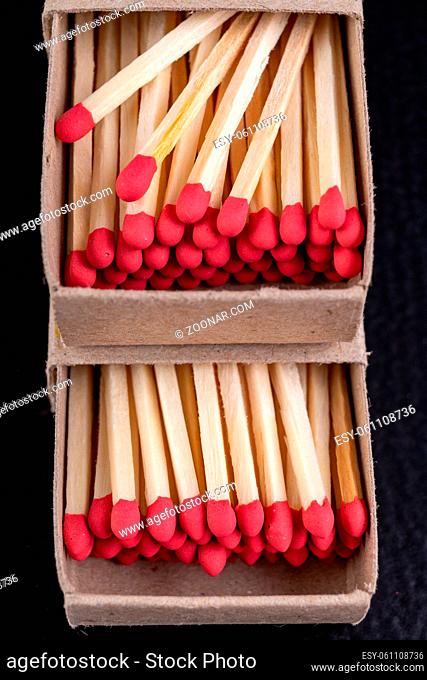 Matches in gray paper boxes. Wooden sticks with sulfur on the tip to ignite the flame. Dark background