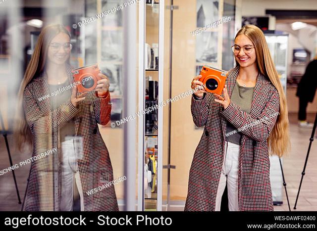 Smiling customer with eyeglasses shopping instant camera in store