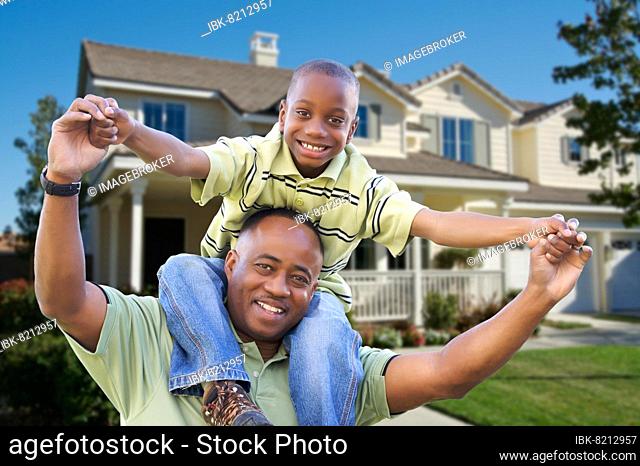 Playful african american father and son in front yard of home