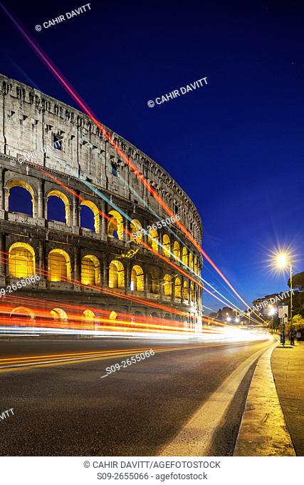 Side view of the Colloseum, viewed from the Piazza del Colosseo at twilight, with vehicular light trails, Campitelli, Rome, Lazio, Italy