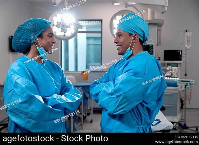 Diverse male and female surgeons wearing face masks and protective clothing in operating theatre