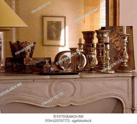 Close-up of silver candlesticks in front of mirror on marble mantelpiece