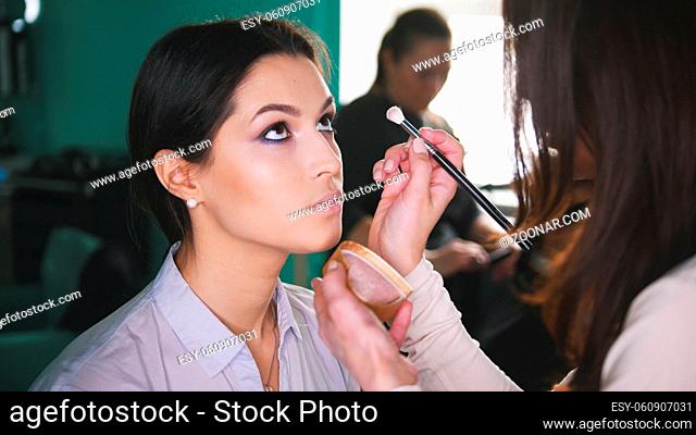 Make-up process at beauty shop for young black haired woman - making visage for eyes, close up shot
