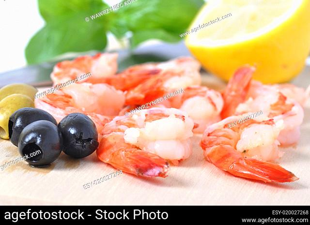 Shrimps, olives, lemon, and basil on board isolated on white bac