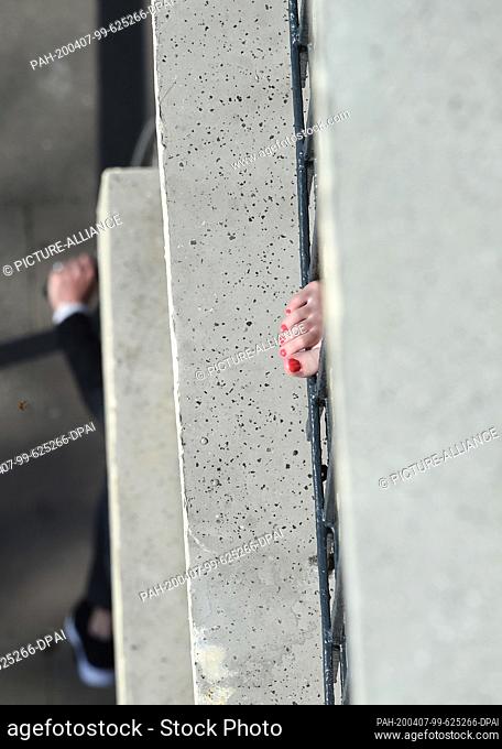01 January 2014, Hamburg: A woman is sunbathing on the balcony and has put her foot through the balcony railing with red painted toenails