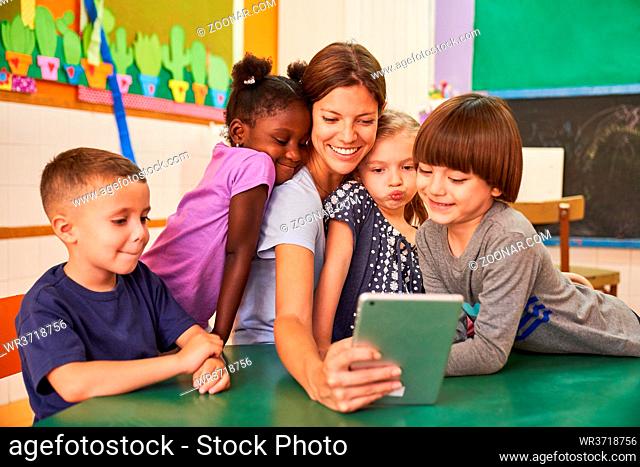 Kindergärtnerin und Kinder machen ein Selfie im internationalen Kindergarten für Social Media