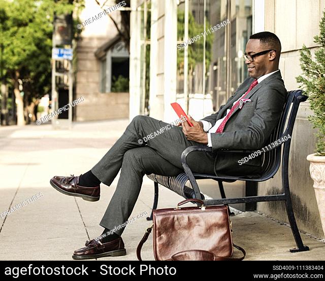 Black businessman using digital tablet on bench