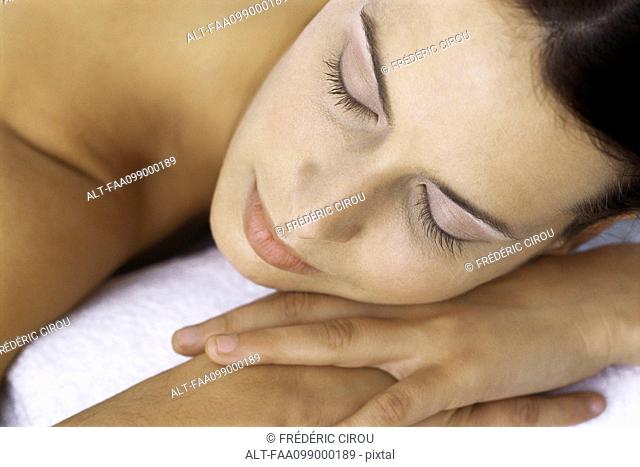 Woman resting head on hands, eyes closed