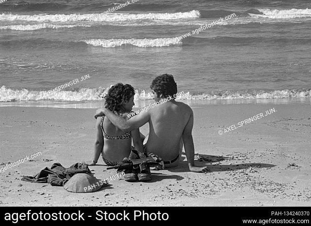 An Israeli soldier sits with his girlfriend on the beach in Tel Aviv, bath in the sea, Mediterranean, private, soldier's boots