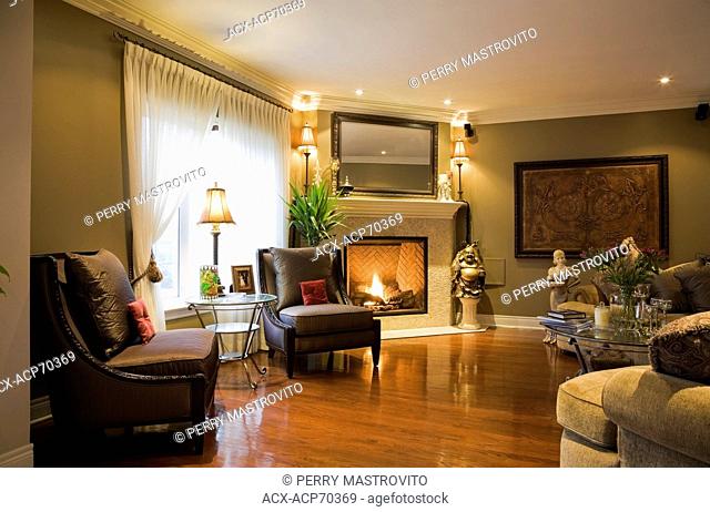 Family room with a gas fireplace and hardwood floor inside a luxurious cottage style residential home, Montreal, Quebec, Canada